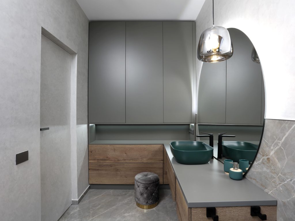 baie moderna cu lavoar verde si mobilier gri